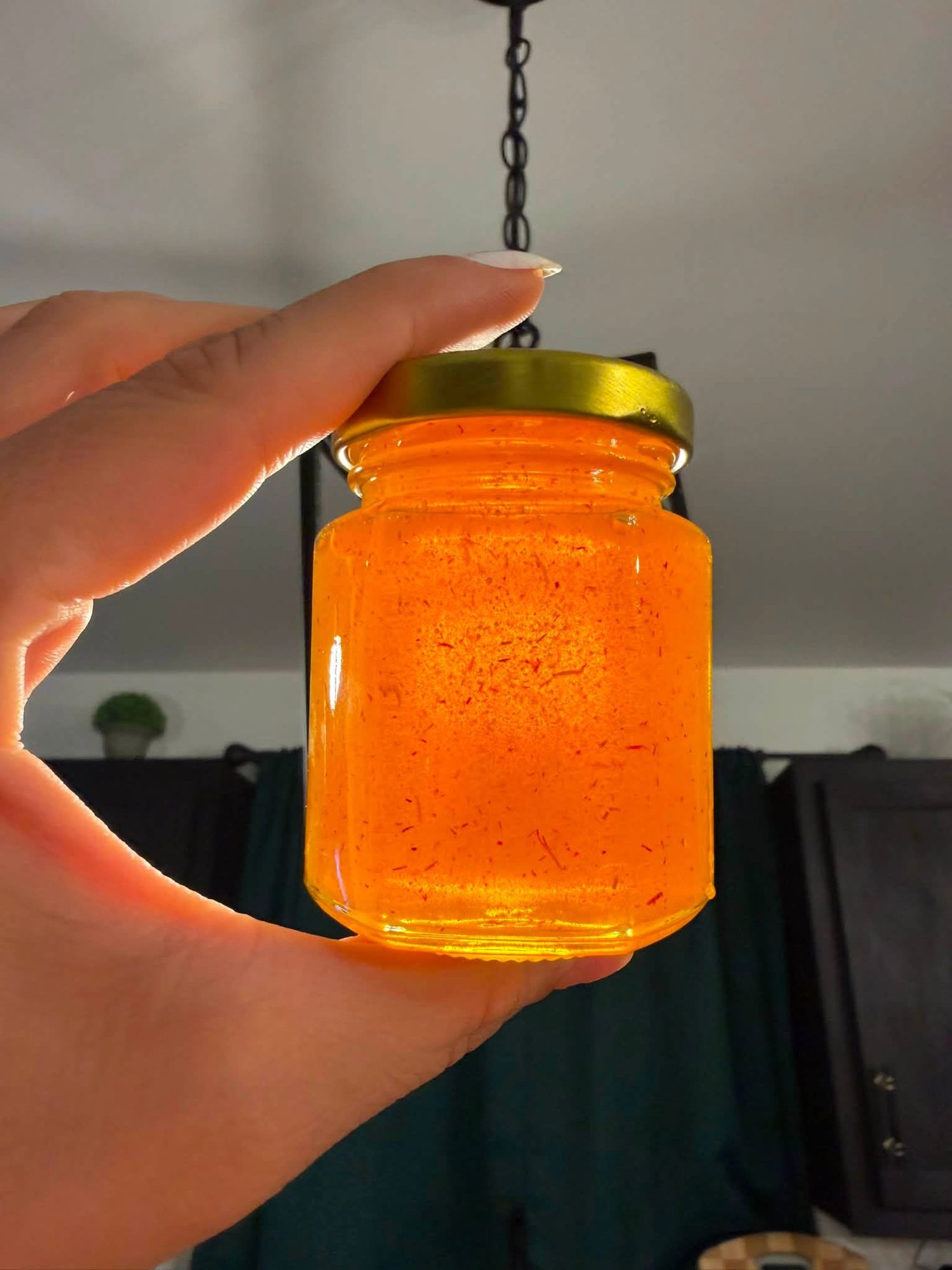 Jar of saffron-infused honey held up to the light
